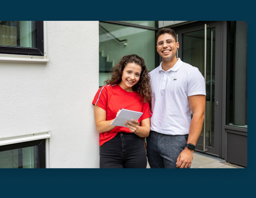 Zwei junge Menschen lachen und halten ein Tablet